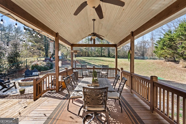 deck featuring an outdoor fire pit, ceiling fan, and a yard