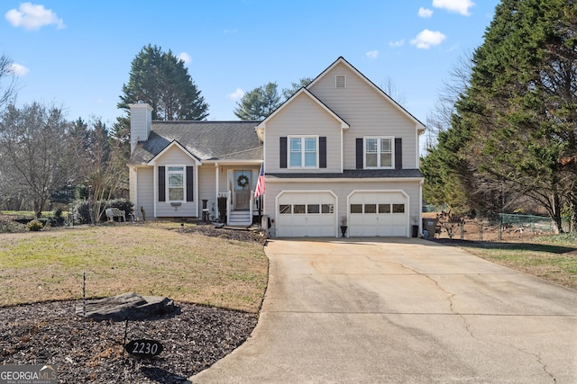 split level home with a chimney, an attached garage, a front yard, fence, and driveway