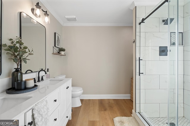 bathroom with crown molding, toilet, a sink, a shower stall, and wood finished floors