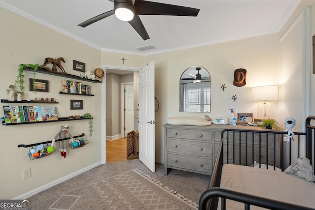 carpeted bedroom with a ceiling fan, visible vents, crown molding, and baseboards