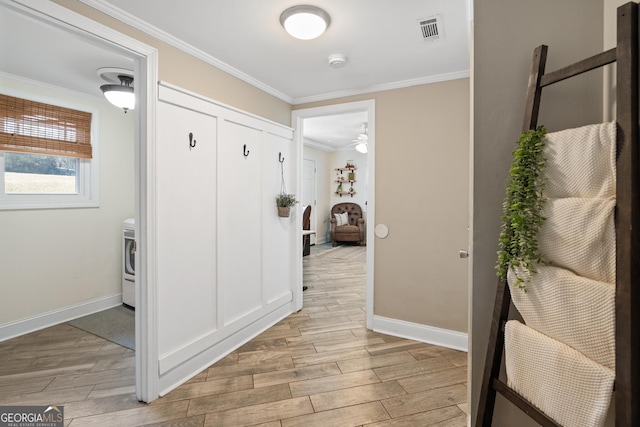 corridor with wood finish floors, crown molding, washer / clothes dryer, visible vents, and baseboards