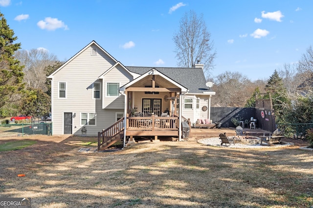 back of house with a fire pit, a lawn, a chimney, fence, and a wooden deck