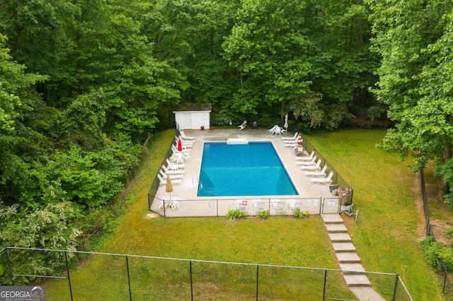 pool with a yard, an outdoor structure, a shed, and fence