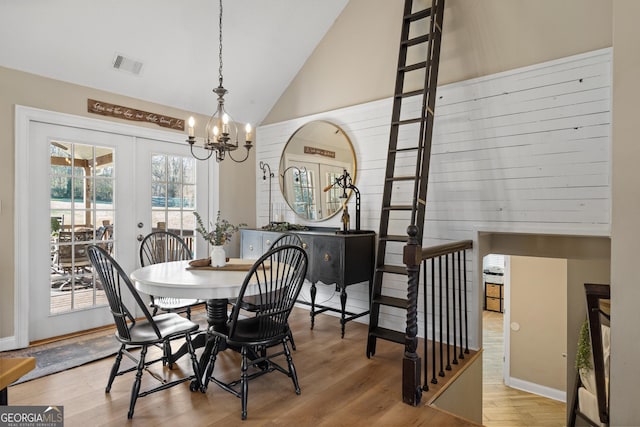 dining area featuring visible vents, a chandelier, light wood-style flooring, french doors, and high vaulted ceiling