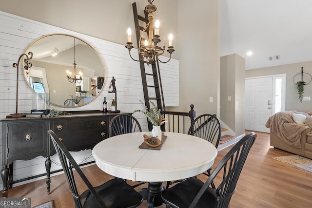 dining area with light wood finished floors, visible vents, and a chandelier