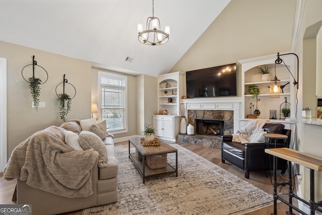 living area with visible vents, wood finished floors, a fireplace, high vaulted ceiling, and a notable chandelier