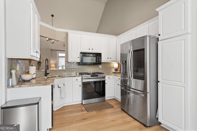 kitchen with lofted ceiling, stainless steel appliances, white cabinets, light stone countertops, and tasteful backsplash