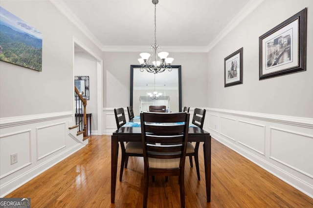 dining room featuring ornamental molding, wood-type flooring, and an inviting chandelier