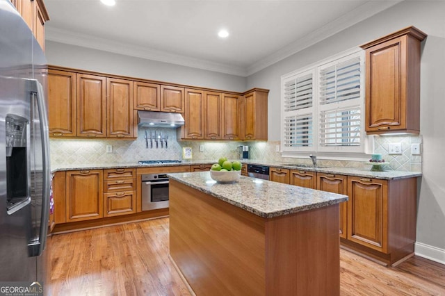 kitchen with light stone counters, appliances with stainless steel finishes, a kitchen island, and light wood-type flooring