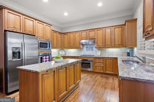 kitchen featuring stainless steel appliances, light stone countertops, a center island, and sink