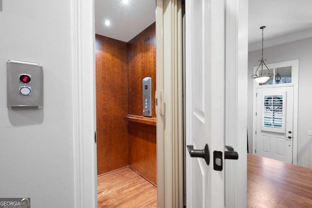 interior details featuring hardwood / wood-style flooring, crown molding, and elevator