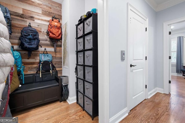 hall with ornamental molding, wooden walls, and light hardwood / wood-style floors