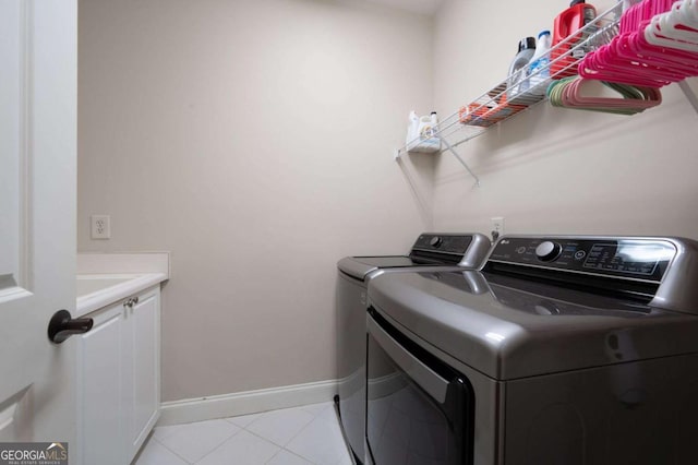 washroom with washer and clothes dryer, cabinets, and light tile patterned flooring