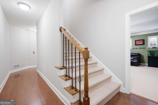 stairs with crown molding and hardwood / wood-style floors