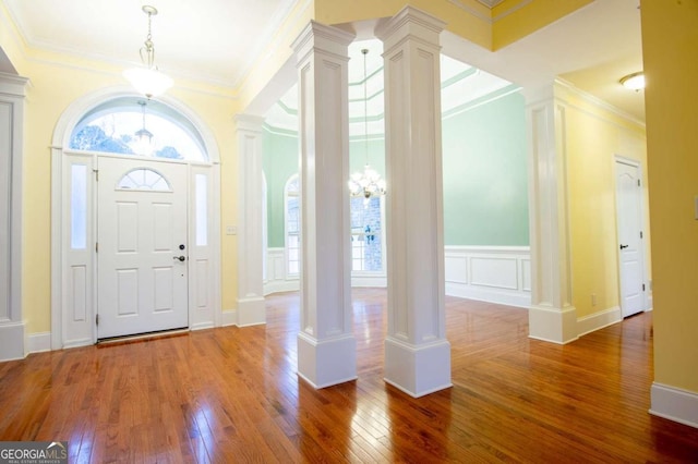 foyer with decorative columns, an inviting chandelier, hardwood / wood-style flooring, and ornamental molding