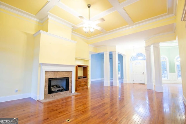 unfurnished living room featuring a high end fireplace, decorative columns, ornamental molding, coffered ceiling, and ceiling fan