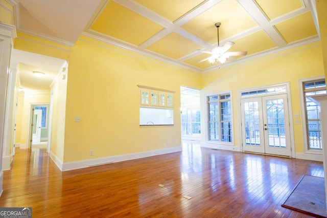 unfurnished living room featuring ceiling fan, french doors, crown molding, and coffered ceiling