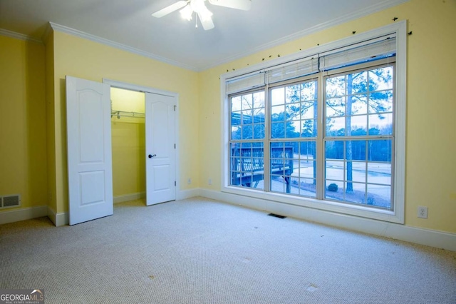 unfurnished bedroom with ceiling fan, light colored carpet, ornamental molding, and a closet