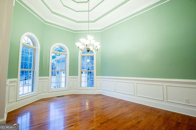 empty room featuring hardwood / wood-style floors, crown molding, a wealth of natural light, and a notable chandelier