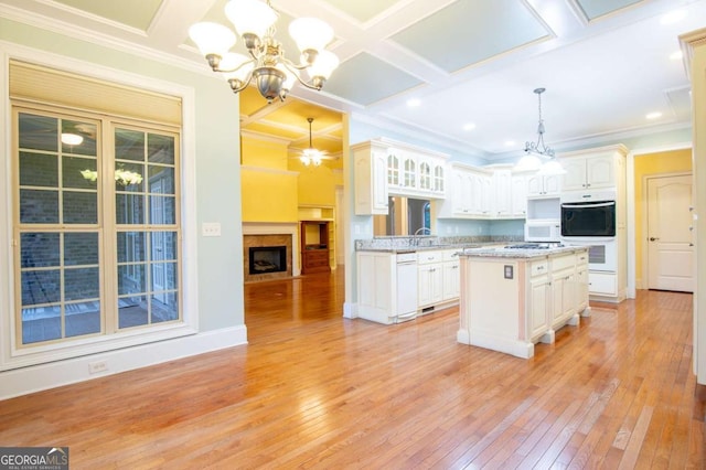 kitchen featuring white appliances, an inviting chandelier, white cabinets, hanging light fixtures, and a kitchen island