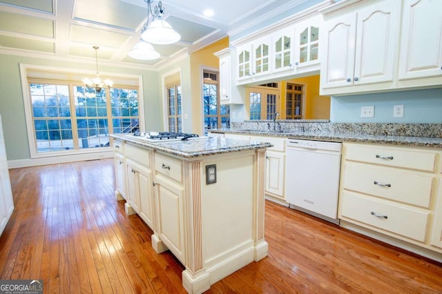 kitchen featuring pendant lighting, a center island, white appliances, light stone countertops, and a chandelier