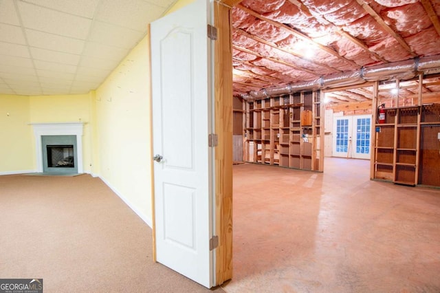 basement with a paneled ceiling and french doors