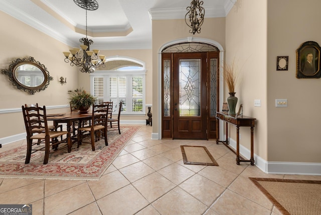 entrance foyer with a tray ceiling, crown molding, light tile patterned flooring, and an inviting chandelier