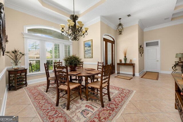 tiled dining area with a raised ceiling, an inviting chandelier, and ornamental molding