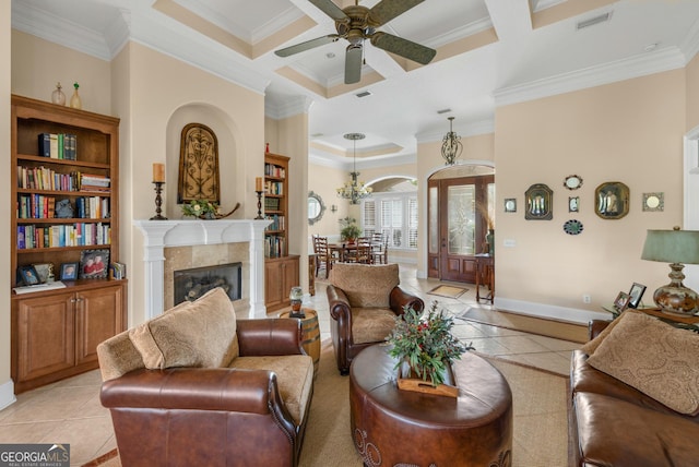 tiled living room with beam ceiling, a tile fireplace, ceiling fan, coffered ceiling, and ornamental molding