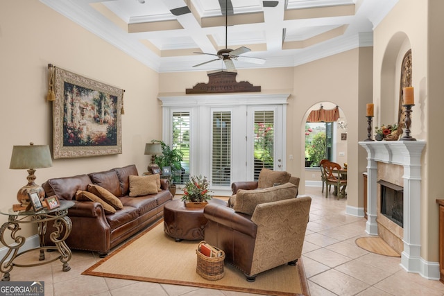 tiled living room featuring coffered ceiling, ceiling fan, crown molding, beamed ceiling, and a fireplace