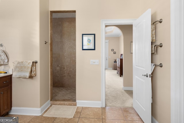 bathroom featuring tile patterned flooring, vanity, and tiled shower