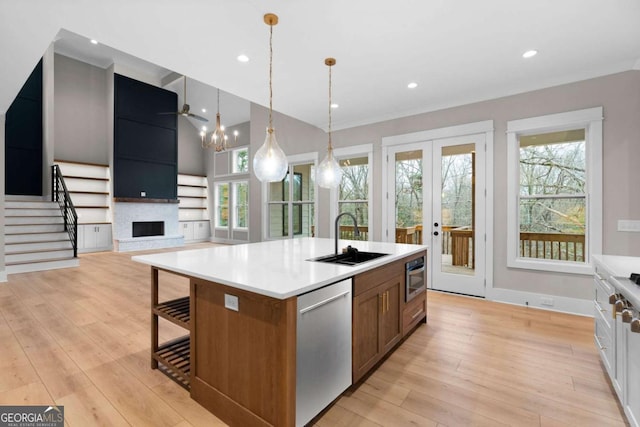 kitchen with sink, stainless steel appliances, pendant lighting, a spacious island, and a fireplace