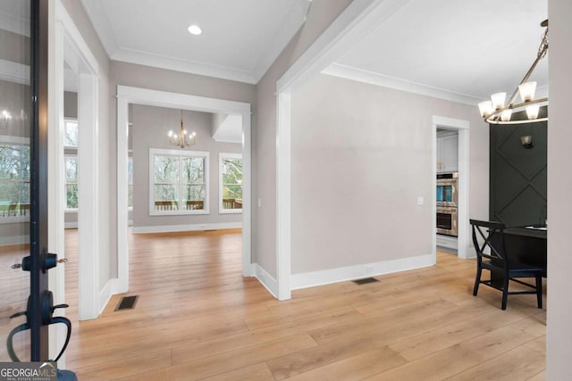 interior space featuring a notable chandelier, light wood-type flooring, and crown molding