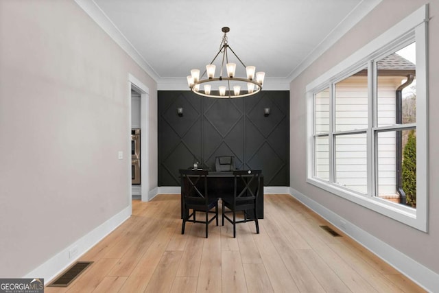 dining space with light hardwood / wood-style flooring, crown molding, and a notable chandelier