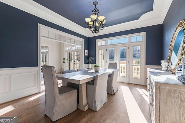 dining space featuring french doors, an inviting chandelier, light hardwood / wood-style flooring, and ornamental molding