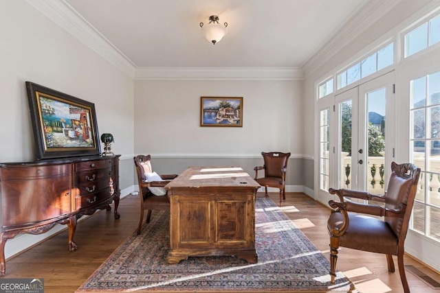 office with light hardwood / wood-style floors, ornamental molding, and french doors