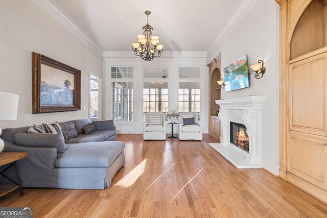 living room with wood-type flooring, ornamental molding, and a notable chandelier