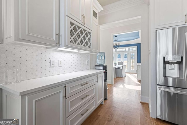 kitchen featuring stainless steel fridge with ice dispenser, ornamental molding, decorative backsplash, white cabinets, and hardwood / wood-style flooring