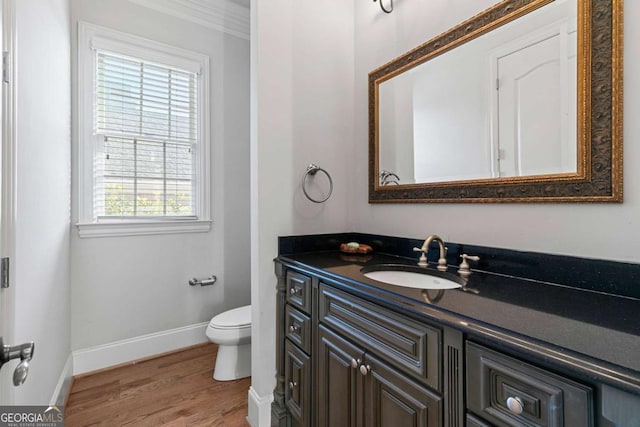 bathroom featuring ornamental molding, vanity, wood-type flooring, and toilet