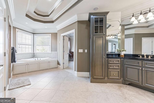 bathroom with vanity, a bathing tub, a raised ceiling, crown molding, and tile patterned flooring