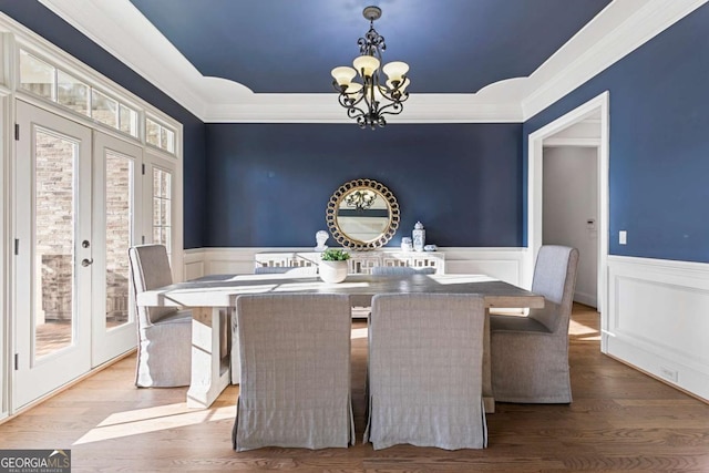 dining room featuring french doors, hardwood / wood-style flooring, crown molding, and a notable chandelier