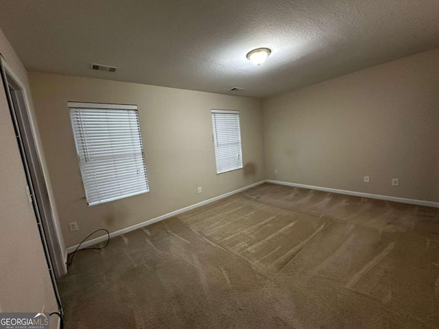 carpeted empty room with a textured ceiling