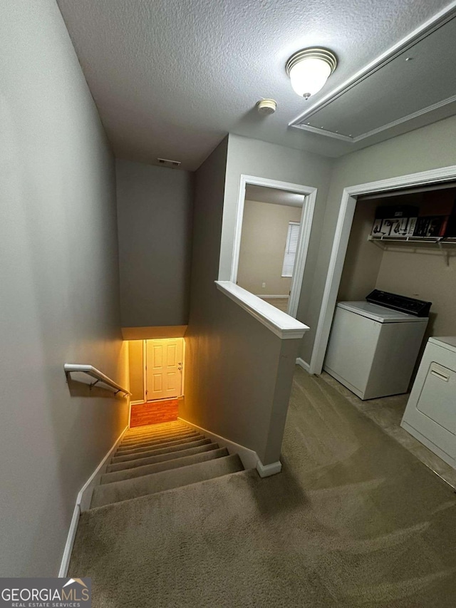 stairway with carpet flooring, separate washer and dryer, and a textured ceiling