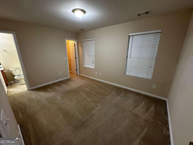 interior space with carpet flooring, a textured ceiling, and connected bathroom