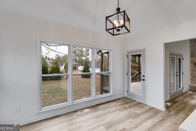 unfurnished dining area with light hardwood / wood-style flooring and a notable chandelier