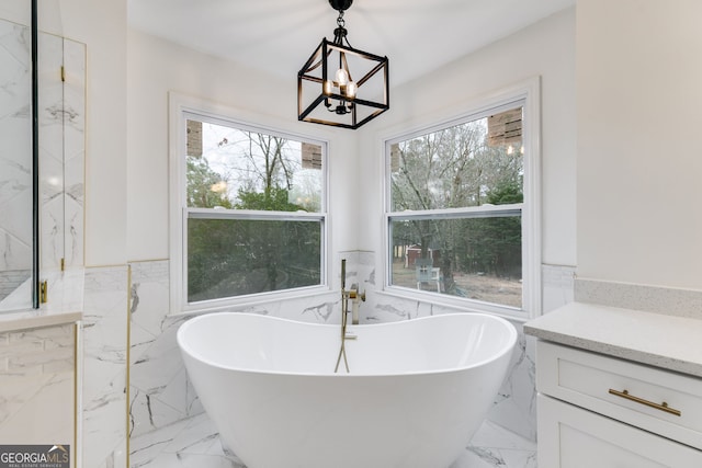 bathroom featuring plenty of natural light, a bathtub, a chandelier, and tile walls