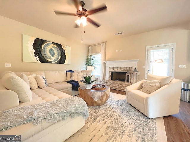 living room with hardwood / wood-style floors, ceiling fan, and a fireplace