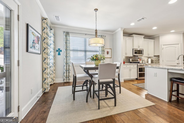 dining room featuring crown molding, sink, and dark wood-type flooring