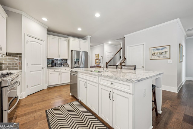 kitchen featuring white cabinetry, sink, stainless steel appliances, and a center island with sink