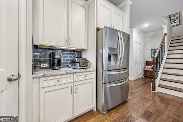 kitchen featuring decorative backsplash, stainless steel refrigerator with ice dispenser, light stone counters, dark wood-type flooring, and white cabinets